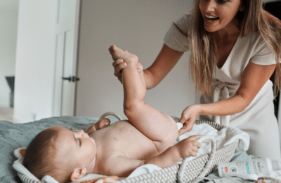 A mom using cloth wipes and Noleo wipe solution to change her baby's diaper.