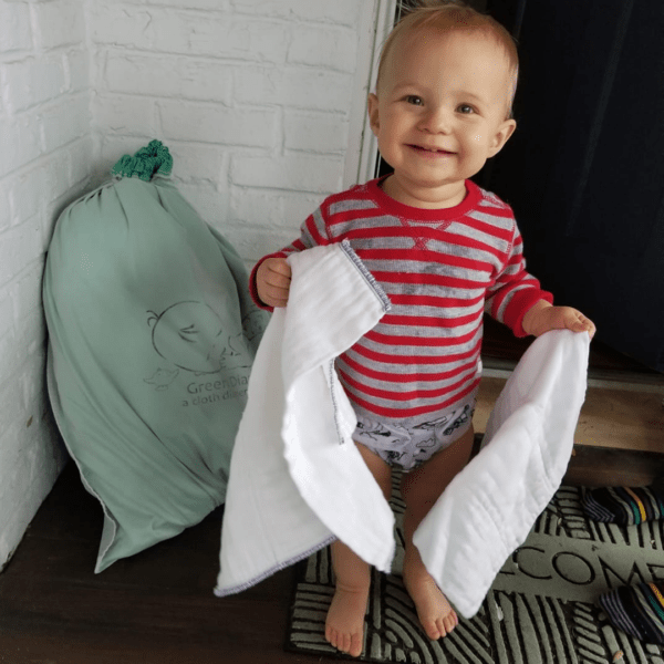 Baby holding cloth diapers in front of his cloth diaper delivery.