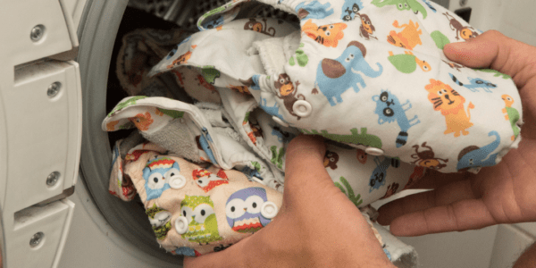 Cloth diapers being loaded into a washer.