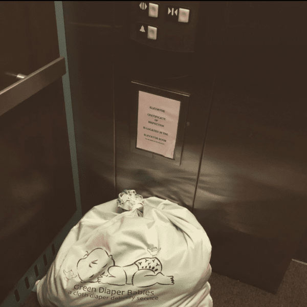 Green Diaper Babies delivery bag being delivered via elevator.