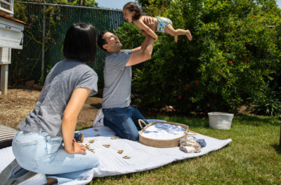 father and mother playing with daughter in a cloth diaper